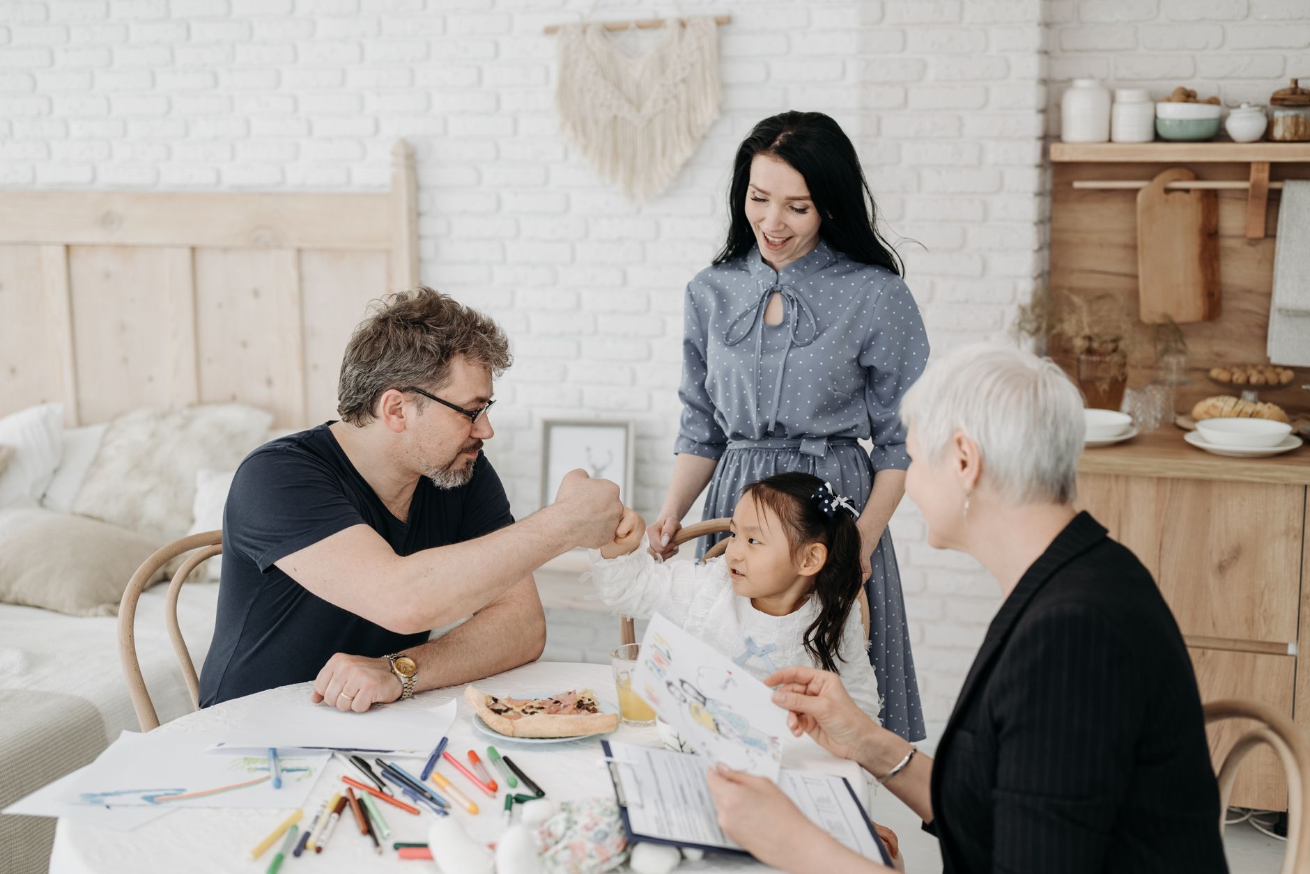 A social worker with a clipboard meets a family and their young daughter at a kitchen table
